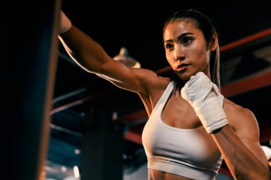 Asyalı kadın Muya Thai boksör eğitimi, spor salonunda kum torbasına yumruk atma. Sağlıklı spor ve spor yaşam tarzı, boks maçı için güç ve dayanıklılık eğitimi. Impetus