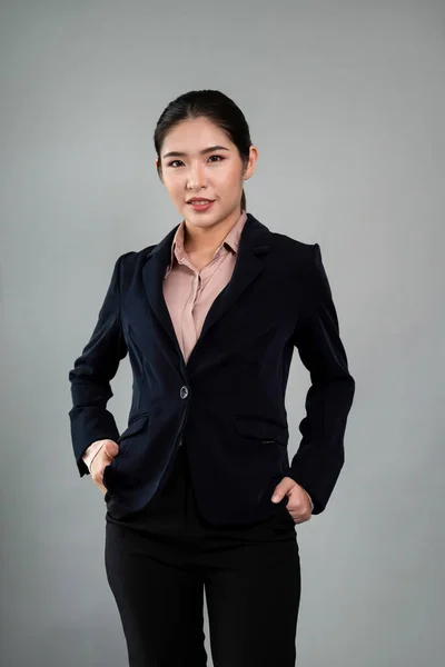 stock image Confident young businesswoman stands on isolated background, posing in formal black suit. Office lady or manager with smart and professional appearance. Enthusiastic