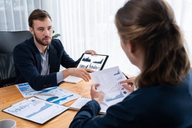 Ofisteki analist ekibi, iş performansını artırmak için tablet ekranında grafik ve grafik olan BI panelini kullanarak çalışma alanındaki pazarlama stratejisi için finansal veri analizi yapmakla meşgul. Varlık