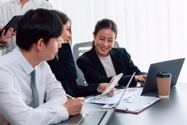 Harmony in office concept as business people analyzing dashboard paper together in workplace. Young colleagues give ideas at manager desk for discussion or strategy planning about project.