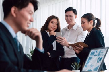 Harmony in office concept as business people analyzing dashboard paper together in workplace. Young colleagues give ideas at manager desk for discussion or strategy planning about project.