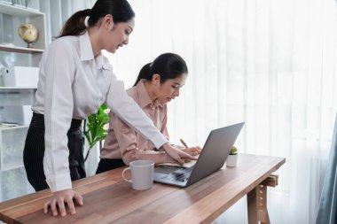 Modern ofis çalışma alanında iş birliği yapan iki genç ofis çalışanı, modern ofis çalışanı olarak profesyonelliklerini sergileyerek, dizüstü bilgisayarda tartışıyorlar ve birlikte çalışıyorlar. Coşkulu.