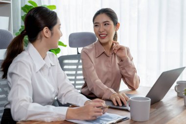 Modern ofis çalışma alanında iş birliği yapan iki genç ofis çalışanı, modern ofis çalışanı olarak profesyonelliklerini sergileyerek, dizüstü bilgisayarda tartışıyorlar ve birlikte çalışıyorlar. Coşkulu.