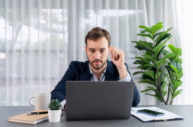 Siyah takım elbiseli bir iş adamı çalışma masasında dizüstü bilgisayarla çalışıyor. Akıllı yönetici finansal verileri araştırıyor ve modern işyerindeki kurumsal dizüstü bilgisayarlarda pazarlama stratejisi planlıyor. Varlık