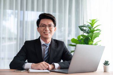 Ofis masasında dizüstü bilgisayarda çalışan bir iş adamı. Akıllı yönetici finansal iş verilerini araştırıyor ya da masada bilgisayarla stratejik iş pazarlaması planlıyor. Sevinçli.