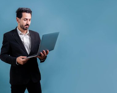 Yenilikçi teknoloji kavramına sahip başarılı bir iş adamı, ayakta duran, dizüstü bilgisayarı tutan ve telif alanı arka planında reklam ya da tanıtım için heyecanla gülümseyen. Coşkulu