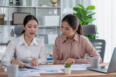 Modern ofis çalışma alanında iş birliği yapan iki genç ofis çalışanı, modern ofis çalışanı olarak profesyonelliklerini sergileyerek, dizüstü bilgisayarda tartışıyorlar ve birlikte çalışıyorlar. Coşkulu.