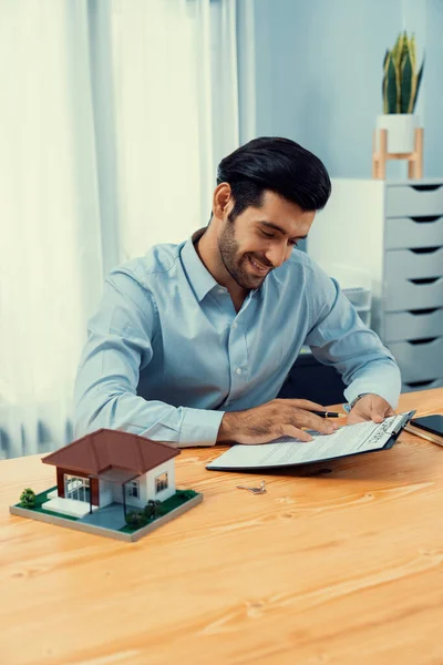 Stock image Satisfied buyer sign house loan or purchase agreement with smile, finalizing the deal. Essential paper for property ownership, including mortgage rate and tax calculation for housing business. Fervent