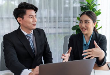 İki Asyalı ofis çalışanı şirket işyerinde birlikte çalışıp tartışıyorlar. Gülümseyen ve planlayan iş arkadaşları, kurumsal çalışma alanındaki dostane çalışma ortamında çalışırlar. Sevinçli.