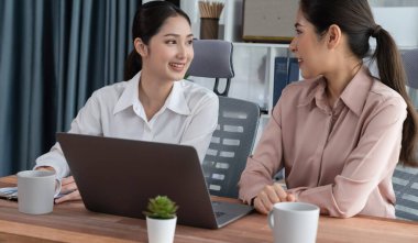 Modern ofis çalışma alanında iş birliği yapan iki genç ofis çalışanı, modern ofis çalışanı olarak profesyonelliklerini sergileyerek, dizüstü bilgisayarda tartışıyorlar ve birlikte çalışıyorlar. Coşkulu.