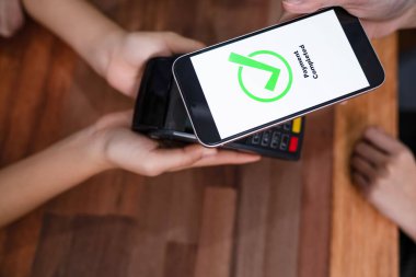 QR kodu parasız ödeme taraması için ekranda gösterilir. Kapalı eller, mobil uygulamadan elektronik işlem yoluyla para aktarmak için akıllı telefonu tutuyor. Hızlı ödeme için barkod teknolojisi. Coşkulu.