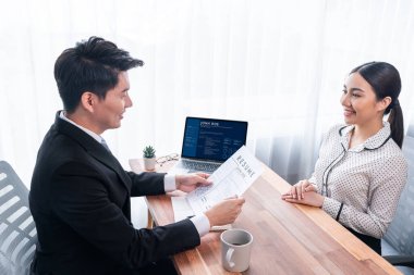 Görüşmeci ve aday arasındaki iş görüşmesi. Asyalı kadın iş başvurusu yapan kişi performansını ve niteliğini dizüstü bilgisayar ve özgeçmişiyle İnsan Kaynakları müdürüne sunar. Sevinçli.