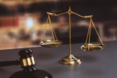 Hukuk firmasında ya da avukatlık bürosunda adalet ve ortak bir hukuki sembol olarak parlak altın dengeli bir ölçek ve ahşap tokmak. Doğruluk ve eşitlik için teraziyi tartın. Eşitlik