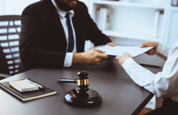 stock image Focus closeup wooden gavel on blur background of lawyer colleagues or drafting legal documents on their workplace at law firm office. Hammer of justice for righteous and equality judgment. Equilibrium