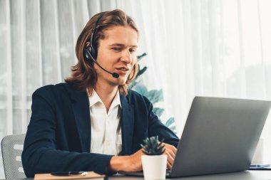 Erkek müşteri hizmetleri operatörü ya da telesales temsilcisi ofiste oturuyor, kulaklık takıyor ve müşteriyle satış desteği ya da kapanış konuşması yapıyor. Çağrı merkezi portresi. Varlık
