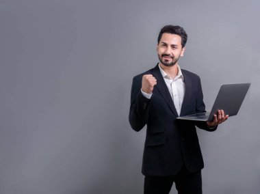 Yenilikçi teknoloji kavramına sahip başarılı bir iş adamı, ayakta duran, dizüstü bilgisayarı tutan ve telif alanı arka planında reklam ya da tanıtım için heyecanla gülümseyen. Coşkulu