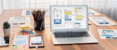 Dizüstü bilgisayar ekranında web ya da mobil uygulama UI UX için dijital ve kağıt kablo tasarımları. Beyin fırtınası ve tasarım uygulama çerçevesi için geliştirici çalışma alanının panoramik görüntüsü. İnceleyin