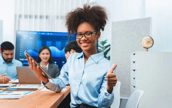 stock image Happy young african businesswoman wearing glasses portrait with group of office worker on meeting with screen display business dashboard in background. Confident office lady at team meeting. Concord