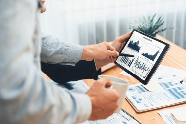 Ofisteki analist ekibi, iş performansını artırmak için tablet ekranında grafik ve grafik olan BI panelini kullanarak çalışma alanındaki pazarlama stratejisi için finansal veri analizi yapmakla meşgul. Varlık