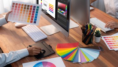 Grafik tasarımcısı, modern dijital stüdyo işyerinde profesyonel grafik ekibiyle benzersiz bir tasarım yaparken bilgisayar dizüstü bilgisayar ve grafik çizim kalemi üzerinde çalışır. Panorama çekimi. İnceleyin