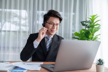 Kendine güvenen Asyalı telesales işadamı modern ofiste kulaklık takarak çalışır, müşterilere ve müşterilere online toplantıda BI gösterge paneli analizi sunar. Modern telesallerin başarısı. Sevinçli.