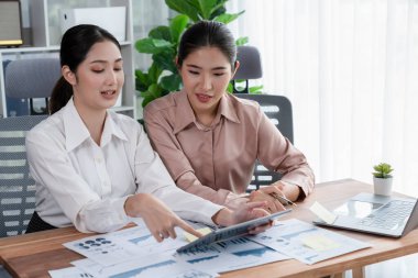 Analist ekip arkadaşı dijital gösterge panelinde finansal verileri tartışır, grafikleri dizüstü bilgisayar ve tablet ekranda analiz eder. Modern ofis pazarlama planlamak için iş zekasını kullanır. Coşkulu.