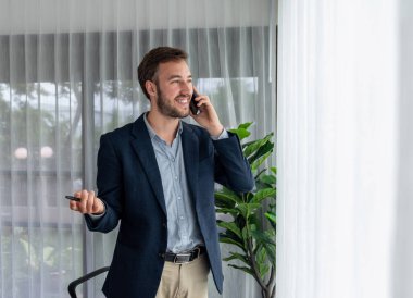 Çalışkan iş adamı, modern ofiste güvenilir bir şekilde müşteriye ikna edici satış çağrıları yapıyor. Ofis çalışanı telefonda konuşuyor ve iş arkadaşlarıyla iş görüşmesi yapıyor. Varlık