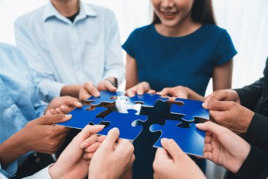 Çeşitli şirket çalışanları, ortaklık ve takım çalışmasını temsil etmek için bulmaca parçalarını birleştirerek ofiste işbirliği yapıyor. Yapboz 'u birleştirerek iş dünyasındaki birlik ve sinerji. Uyum
