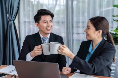 İki Asyalı ofis çalışanı iş yerinde kahve molası veriyor. İş arkadaşları gülümsüyor ve bir fincan kahve içerken sosyalleşiyorlar. Kurumsal çalışma alanına dostane çalışma ortamı ekliyorlar. Sevinçli.