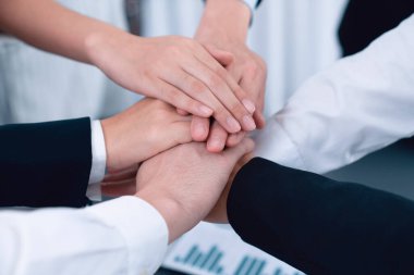 Top view closeup business team of suit-clad businesspeople join hand stack together. Colleague collaborate and work together to promote harmony and teamwork concept in office workplace.