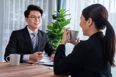 İki Asyalı ofis çalışanı şirket işyerinde birlikte çalışıp tartışıyorlar. Gülümseyen ve planlayan iş arkadaşları, kurumsal çalışma alanındaki dostane çalışma ortamında çalışırlar. Sevinçli.