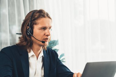 Erkek müşteri hizmetleri operatörü ya da telesales temsilcisi ofiste oturuyor, kulaklık takıyor ve müşteriyle satış desteği ya da kapanış konuşması yapıyor. Çağrı merkezi portresi. Varlık