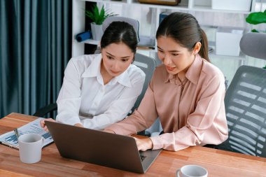 Modern ofis çalışma alanında iş birliği yapan iki genç ofis çalışanı, modern ofis çalışanı olarak profesyonelliklerini sergileyerek, dizüstü bilgisayarda tartışıyorlar ve birlikte çalışıyorlar. Coşkulu.