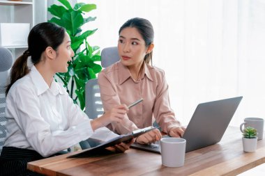 Modern ofis çalışma alanında iş birliği yapan iki genç ofis çalışanı, modern ofis çalışanı olarak profesyonelliklerini sergileyerek, dizüstü bilgisayarda tartışıyorlar ve birlikte çalışıyorlar. Coşkulu.