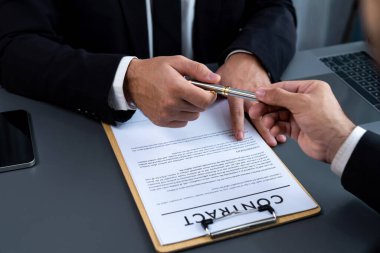 İş anlaşması yapılırken iki işadamı masanın karşısında oturuyor. Şirket avukatı, sözleşmeyi imzalaması için müvekkiline ya da ortağına kalem veriyor ve anlaşmayı imzayla imzalıyor. Coşkulu