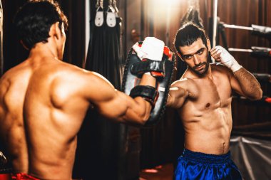 Asyalı ve Kafkasyalı Muay Thai boksörü boks antrenmanında boks antrenmanında boks antrenörüne yumruk atma, Muay Thai boks tekniği ve becerilerini sergileme. Impetus