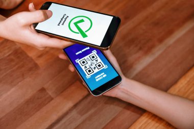 QR kodu parasız ödeme taraması için ekranda gösterilir. Kapalı eller, mobil uygulamadan elektronik işlem yoluyla para aktarmak için akıllı telefonu tutuyor. Hızlı ödeme için barkod teknolojisi. Coşkulu.