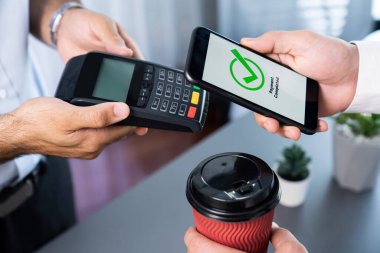 NFC QR kod cihazı ile el ele tutuşan akıllı telefon, hızlı dijital işlemler için temas kurulamayan ödeme kodlarını tarıyor. Modern yaşam tarzı ödeme teknolojisi için cep telefonundaki online bankacılık uygulaması. coşkulu