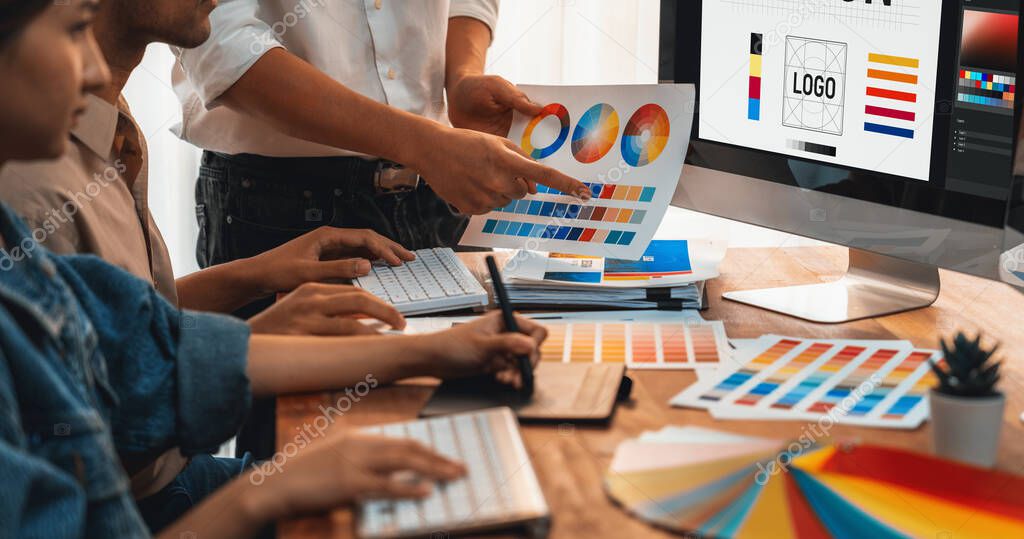 Graphic designer work on computer laptop and with graphic drawing pen while brainstorming unique design with professional graphic team in modern digital studio workplace. Panorama shot. Scrutinize