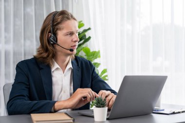 Erkek müşteri hizmetleri operatörü ya da telesales temsilcisi ofiste oturuyor, kulaklık takıyor ve müşteriyle satış desteği ya da kapanış konuşması yapıyor. Çağrı merkezi portresi. Varlık