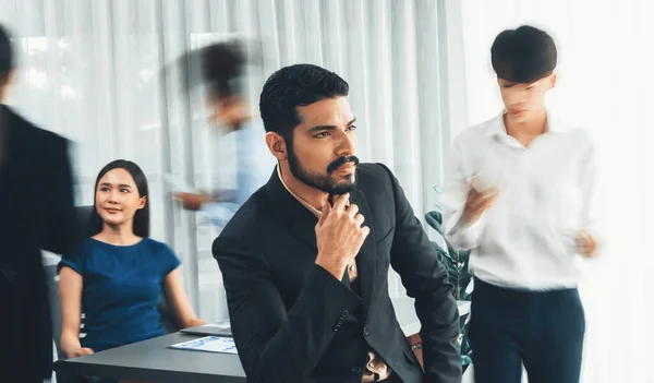 stock image Businessman portrait poses confidently with diverse coworkers in busy meeting room in motion blurred background. Multicultural team works together for business success. Concord