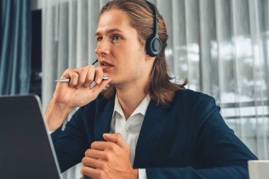 Erkek müşteri hizmetleri operatörü ya da telesales temsilcisi ofiste oturuyor, kulaklık takıyor ve müşteriyle satış desteği ya da kapanış konuşması yapıyor. Çağrı merkezi portresi. Varlık