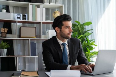 Modern ofis masasındaki modern profesyonel iş adamı çalışmak ve notlar yazmak için dizüstü bilgisayar kullanıyor. Ofisinde bilgisayar defteri üzerinde çalışan çalışkan bir ofis çalışanı. coşkulu