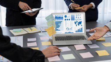 Analizci ekibi yaratıcı ve analitik beyin fırtınası fikri için bilgisayar ekranında BI veri paneli olan yapışkan bir not kullanıyor. Pazarlama stratejisi için finansal veri görselleştirme teknolojisini analiz et. Dahi.