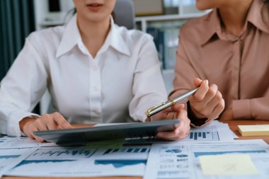 Analist ekip arkadaşı dijital gösterge panelinde finansal verileri tartışır, grafikleri dizüstü bilgisayar ve tablet ekranda analiz eder. Modern ofis pazarlama planlamak için iş zekasını kullanır. Coşkulu.