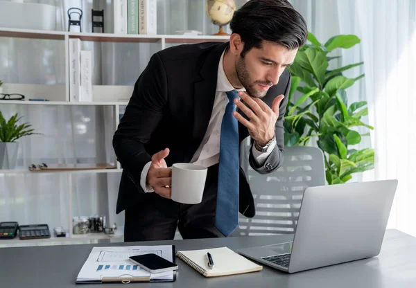 stock image Modern professional businessman at modern office desk using laptop to work with coffee in his hand. Diligent office worker working on computer notebook in his office work space. fervent