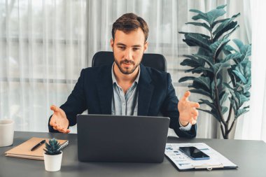 İşadamı ofis masasından sanal ofis toplantısı düzenliyor ve uzaktan çalışanlarla uzak iletişim kurmak için dizüstü bilgisayardaki Webinar uygulamasını kullanarak çevrimiçi video konferansını tartışıyor. Varlık