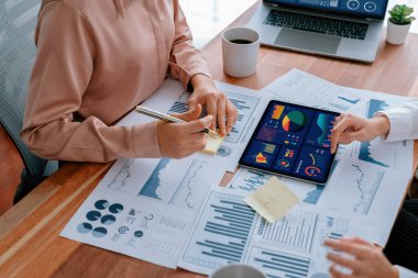 Analist ekip arkadaşı dijital gösterge panelinde finansal verileri tartışır, grafikleri dizüstü bilgisayar ve tablet ekranda analiz eder. Modern ofis pazarlama planlamak için iş zekasını kullanır. Coşkulu.