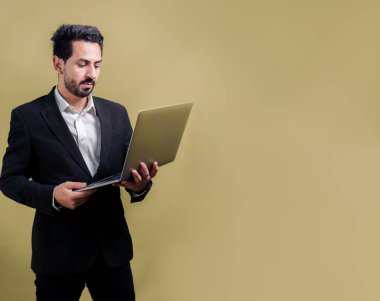 Yenilikçi teknoloji kavramına sahip başarılı bir iş adamı, ayakta duran, dizüstü bilgisayarı tutan ve telif alanı arka planında reklam ya da tanıtım için heyecanla gülümseyen. Coşkulu