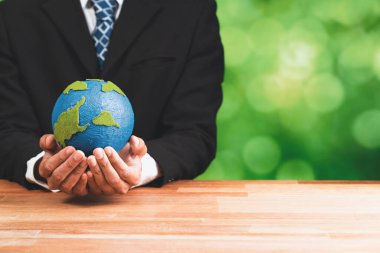 İşadamı temiz enerji ve sıfır CO2 emisyonu kullanarak sürdürülebilir dünya için çevresel farkındalığın sembolü olarak kağıt toprağı elinde tutuyor. Dünya 'yı kurtarmak için yeşil politikası olan çevre dostu bir şirket. Değiştir